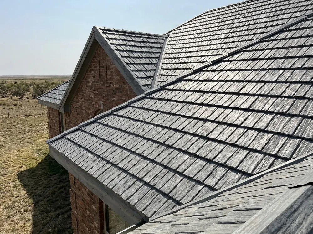 Weathered-grey steel shingles shaped like wood shakes on a gabled roof